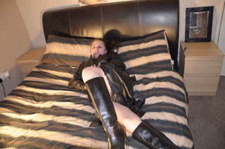 girl-in-leather-gloves-putting-on-leather-boots-in-leather-jacket-in-room